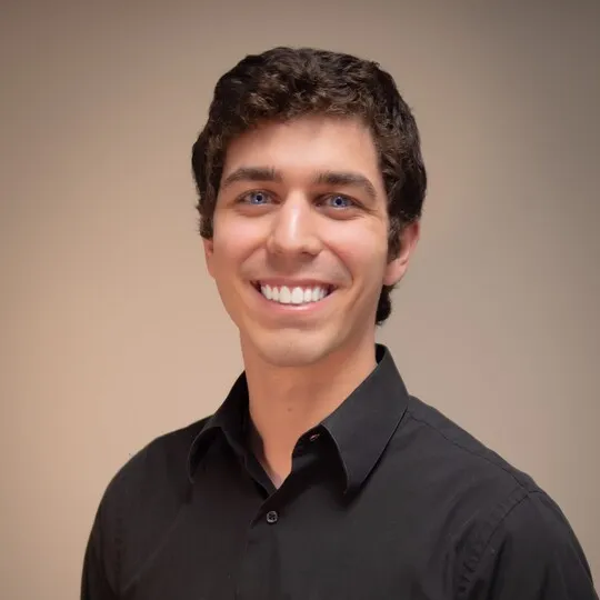 man with brown hair and black shirt smiling